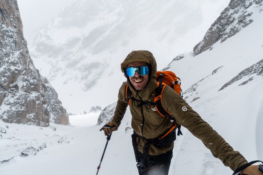 Michelino climbing a snowy couloir with poles